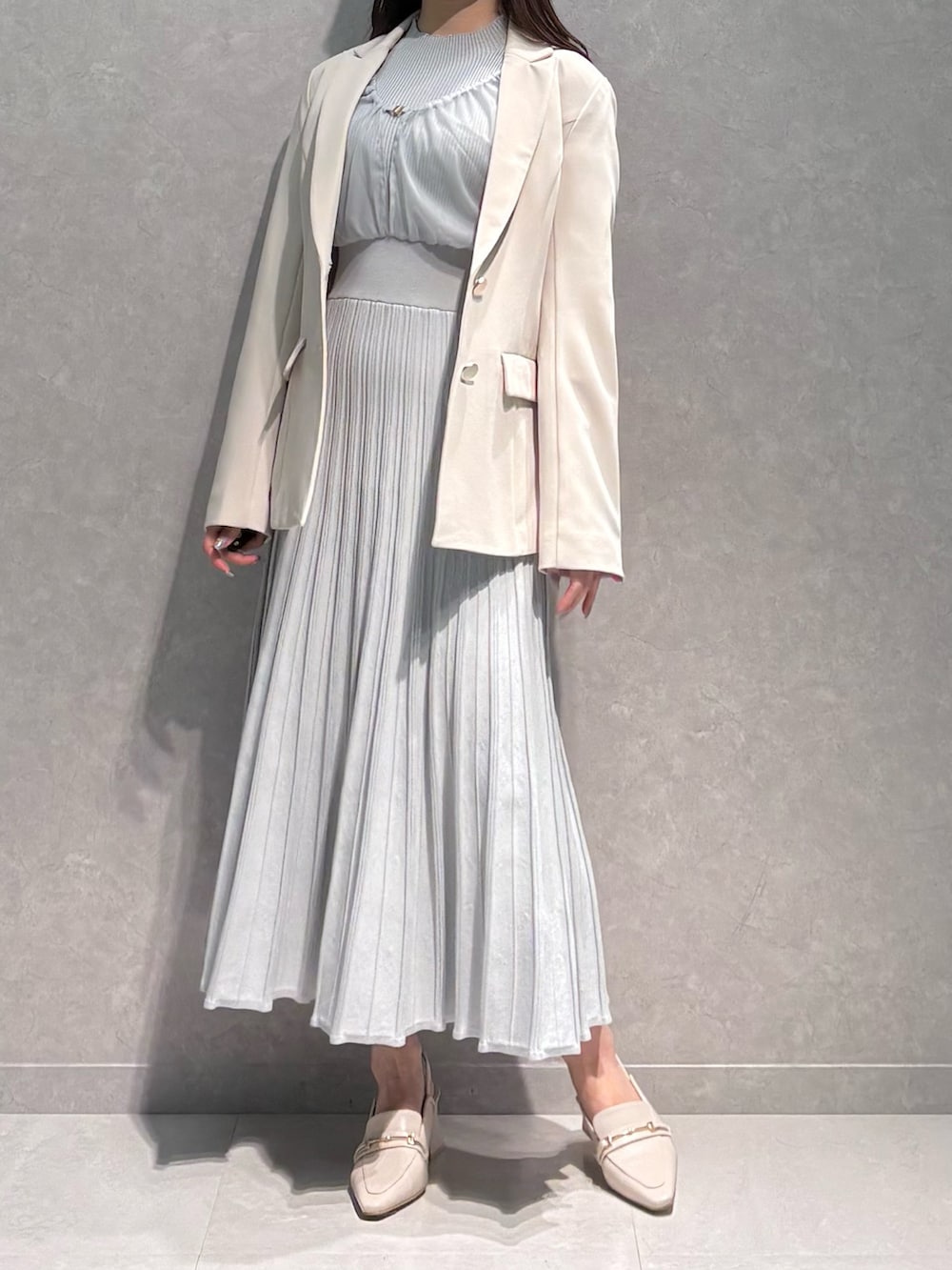 グレー系のワンピース、ホワイト系のテーラードジャケット、ホワイト系のパンプスを着用したレディースの春コーディネートの2枚目の写真