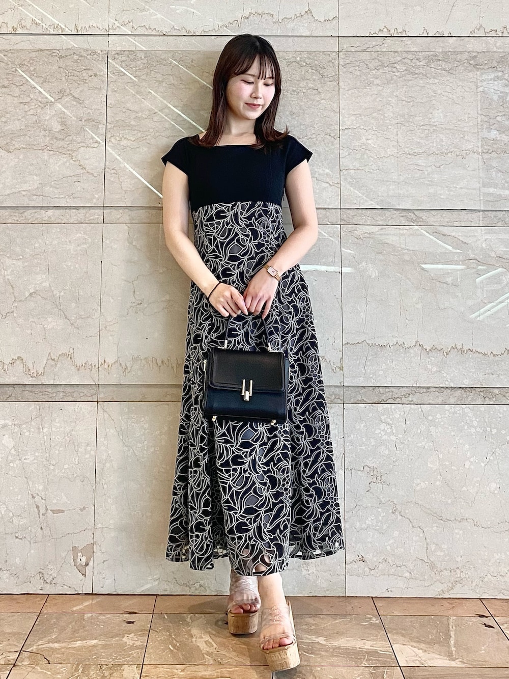 ブラック系のハンドバッグ、その他のサンダル、ブラック系のワンピースを着用したレディースの春コーディネートの2枚目の写真