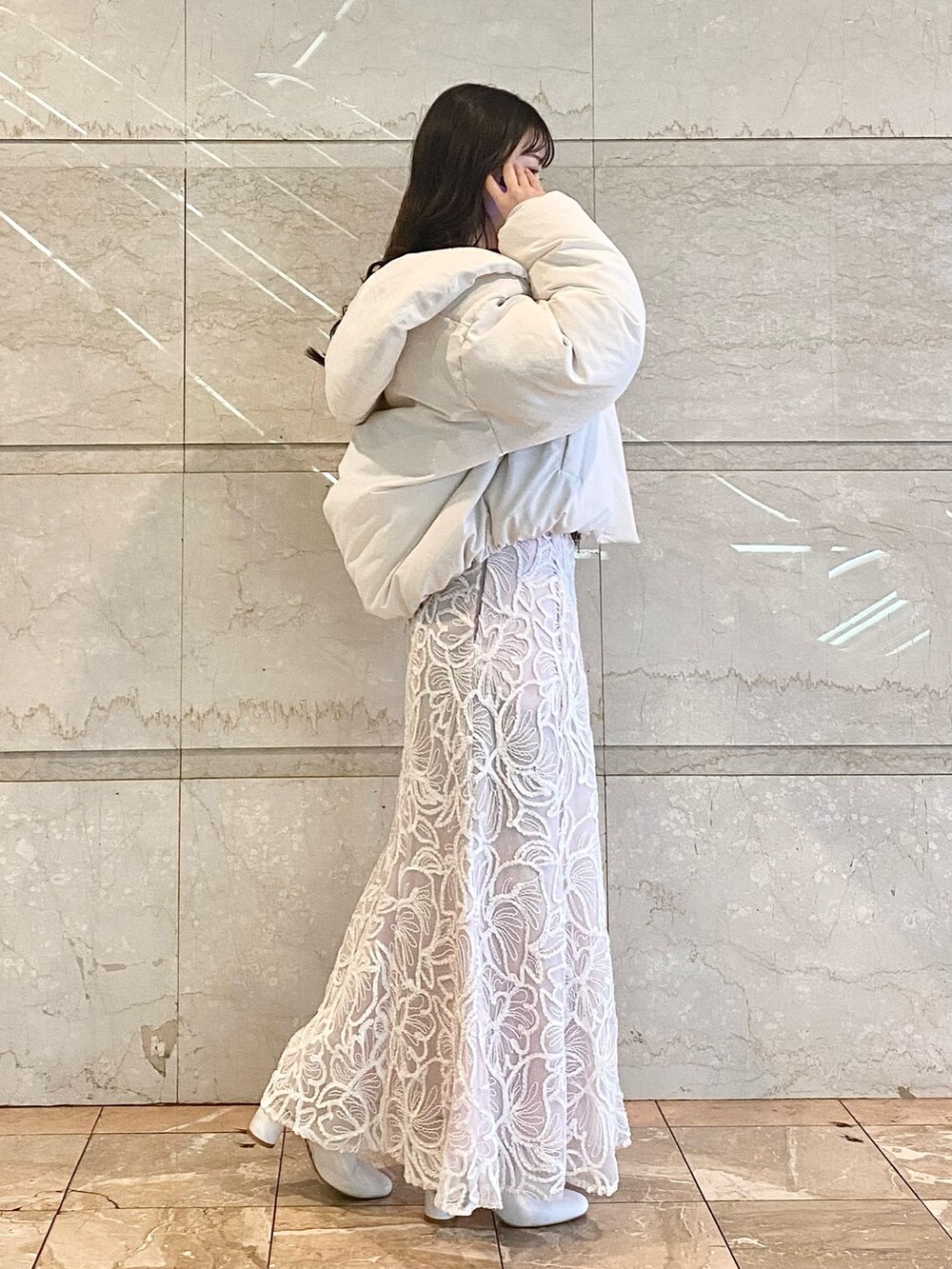 ピンク系のスカート、ホワイト系のニット/セーター、ホワイト系のダウンジャケット/コートを着用したレディースの冬コーディネートの5枚目の写真