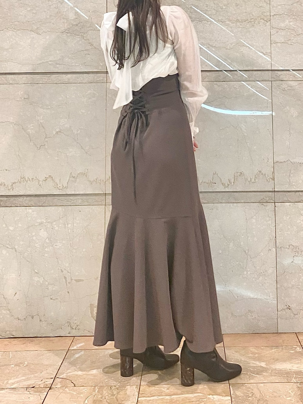 ブラウン系のスカート、ホワイト系のシャツ/ブラウス、ブラウン系のブーツを着用したレディースの冬コーディネートの5枚目の写真