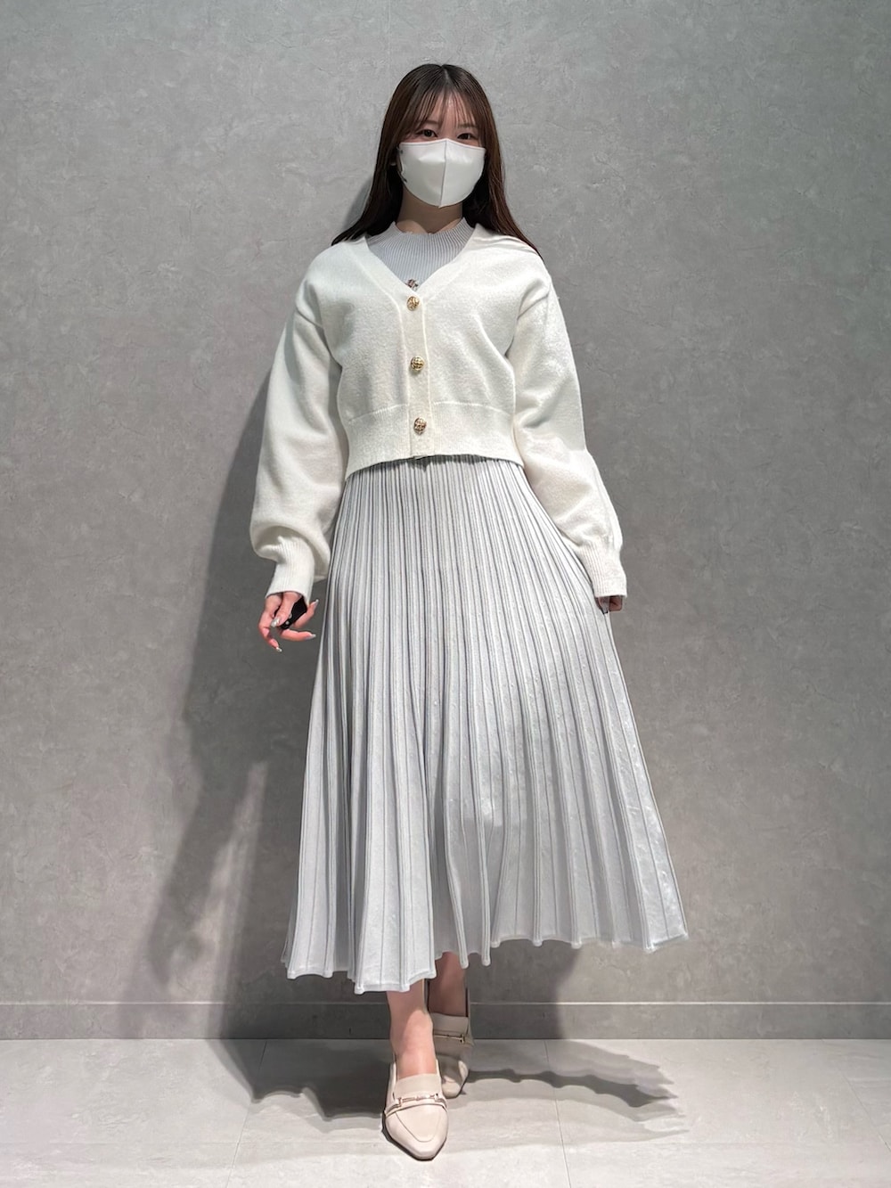 グレー系のワンピース、ホワイト系のカーディガン/ボレロ、ホワイト系のパンプスを着用したレディースの春コーディネートの2枚目の写真