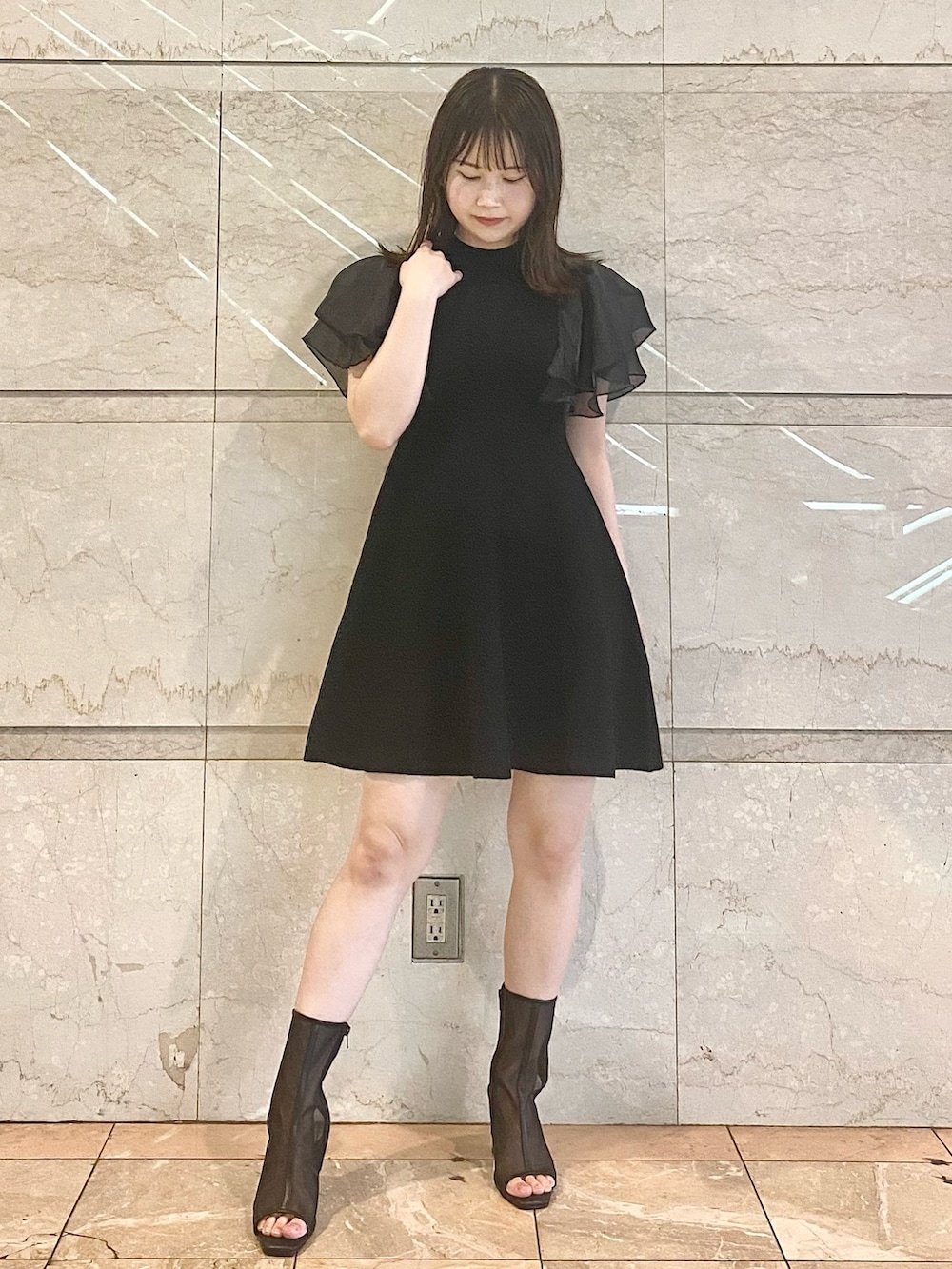 ブラック系のワンピース、ブラック系のブーツを着用したレディースの春コーディネートの2枚目の写真