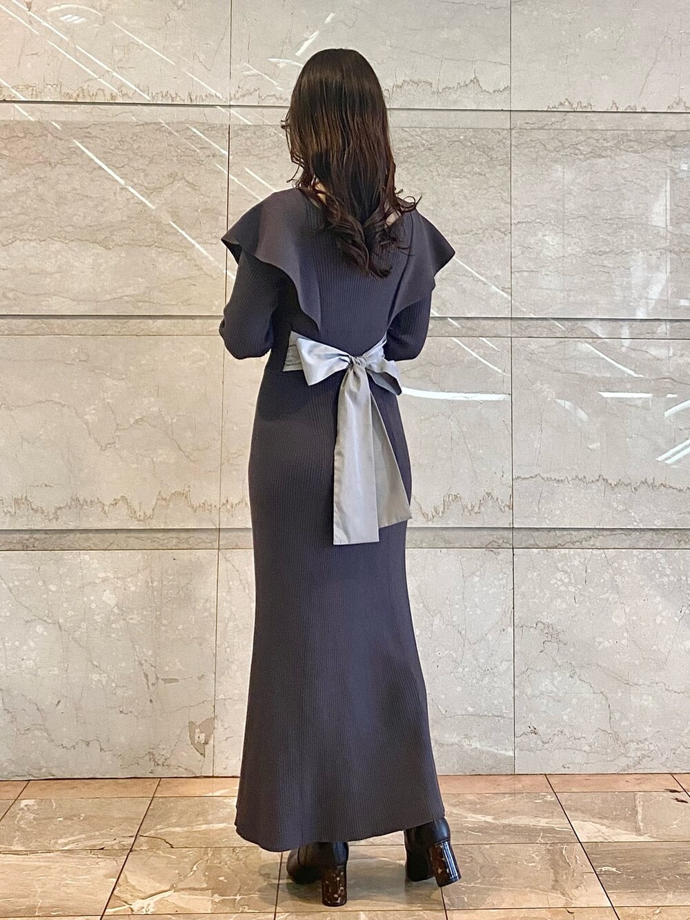 グレー系のワンピース、ブラック系のブーツ、ブラック系のハンドバッグを着用したレディースの冬コーディネートの5枚目の写真