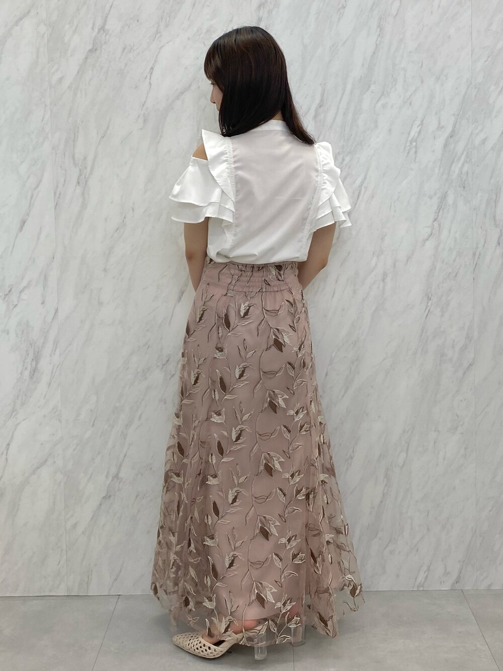 ピンク系のスカート、ホワイト系のシャツ/ブラウス、ホワイト系のパンプスを着用したレディースの夏コーディネートの2枚目の写真