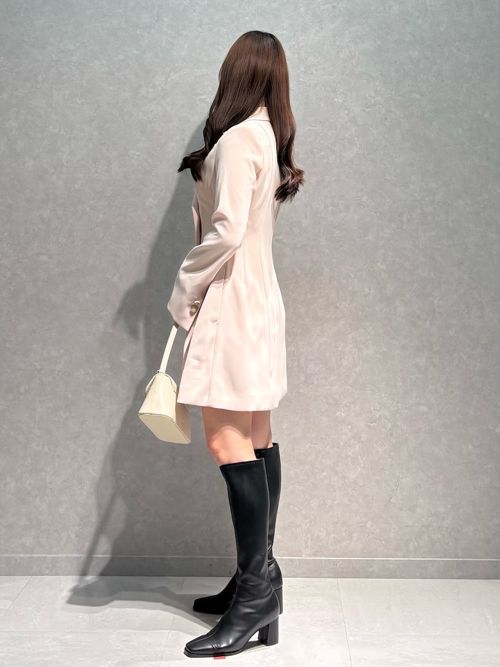 ピンク系のワンピース、ホワイト系のハンドバッグ、ブラック系のブーツを着用したレディースの春コーディネートの4枚目の写真
