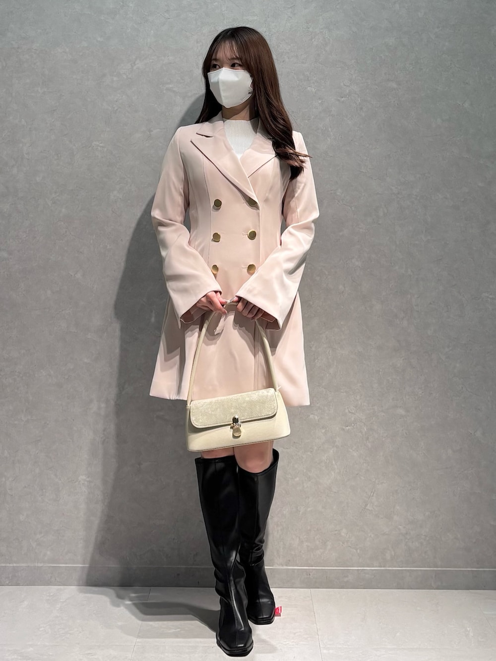 ピンク系のワンピース、ホワイト系のハンドバッグ、ブラック系のブーツを着用したレディースの春コーディネートの2枚目の写真