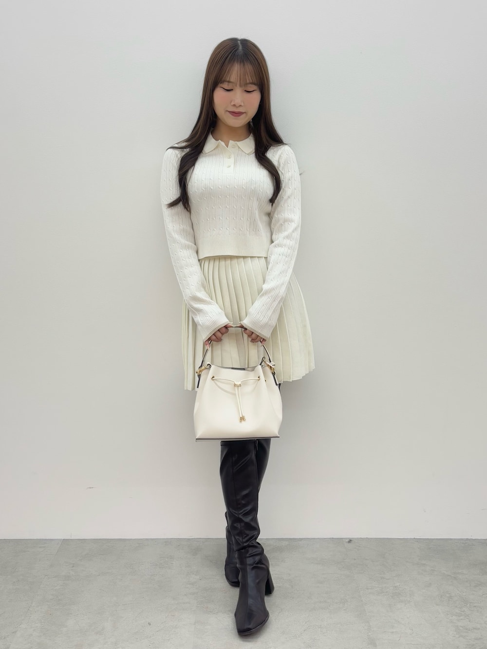 ブラウン系のブーツ、ホワイト系のショルダーバッグ、ホワイト系のワンピースを着用したレディースの冬コーディネートの2枚目の写真
