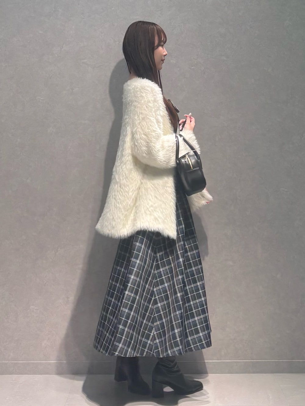 グリーン系のワンピース、ブラック系のハンドバッグ、ブラック系のブーツを着用したレディースの秋コーディネートの3枚目の写真