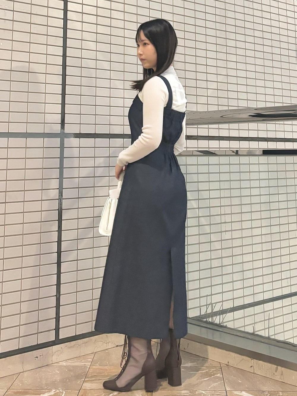 ホワイト系のハンドバッグ、ブラウン系のブーツ、ホワイト系のニット/セーターを着用したレディースの秋コーディネートの3枚目の写真