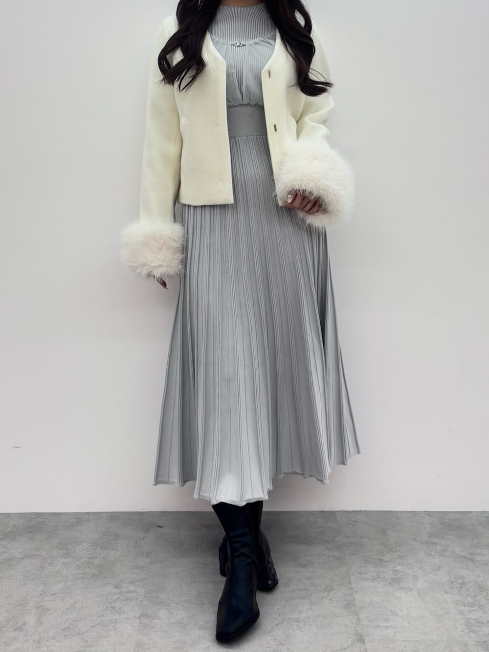 ブラック系のブーツ、ホワイト系のその他アウター、グレー系のワンピースを着用したレディースの冬コーディネートの3枚目の写真