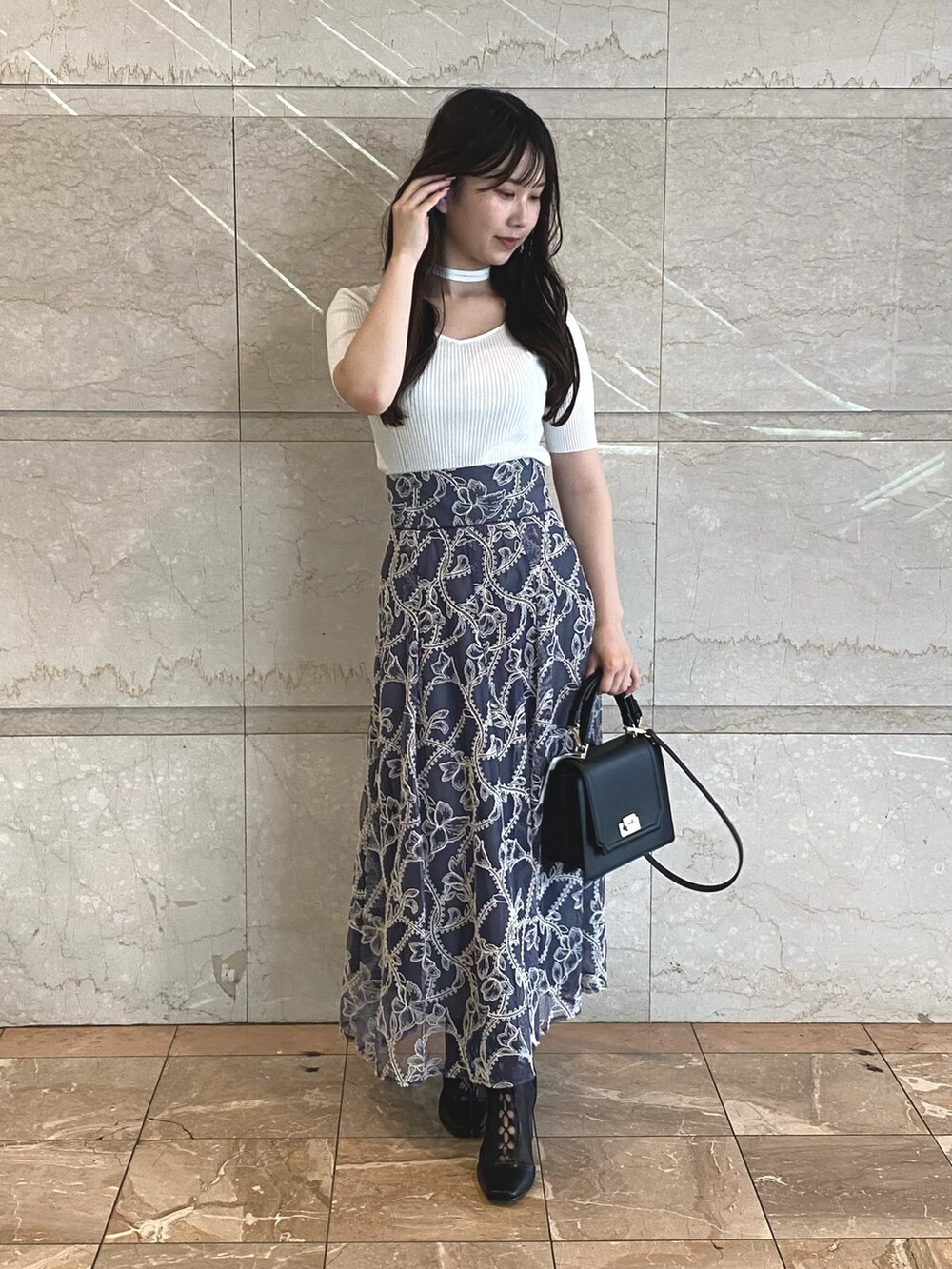 グレー系のスカート、ホワイト系のニット/セーター、ブラック系のブーツを着用したレディースの夏コーディネートの2枚目の写真