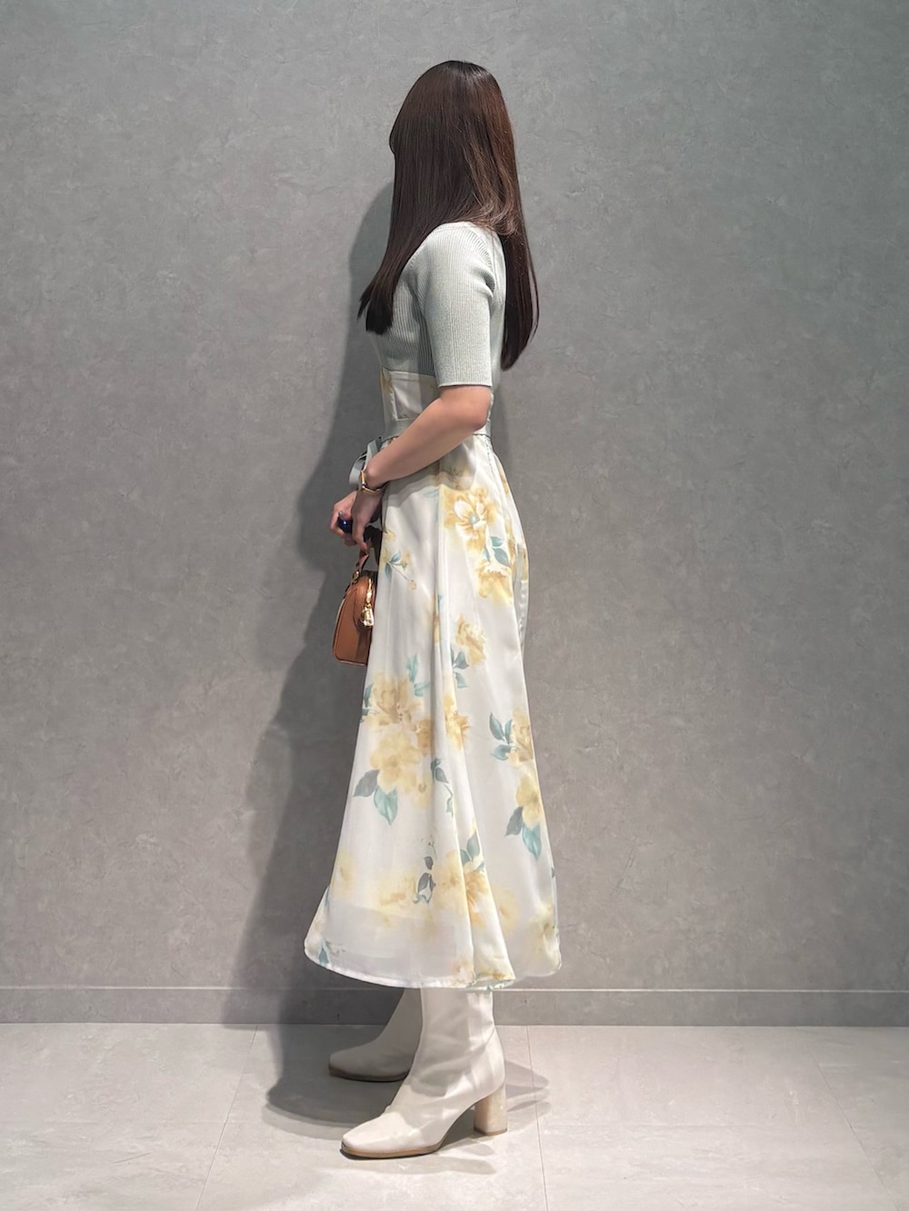 グリーン系のワンピース、ホワイト系のブーツ、ブラウン系のハンドバッグを着用したレディースの春コーディネートの4枚目の写真