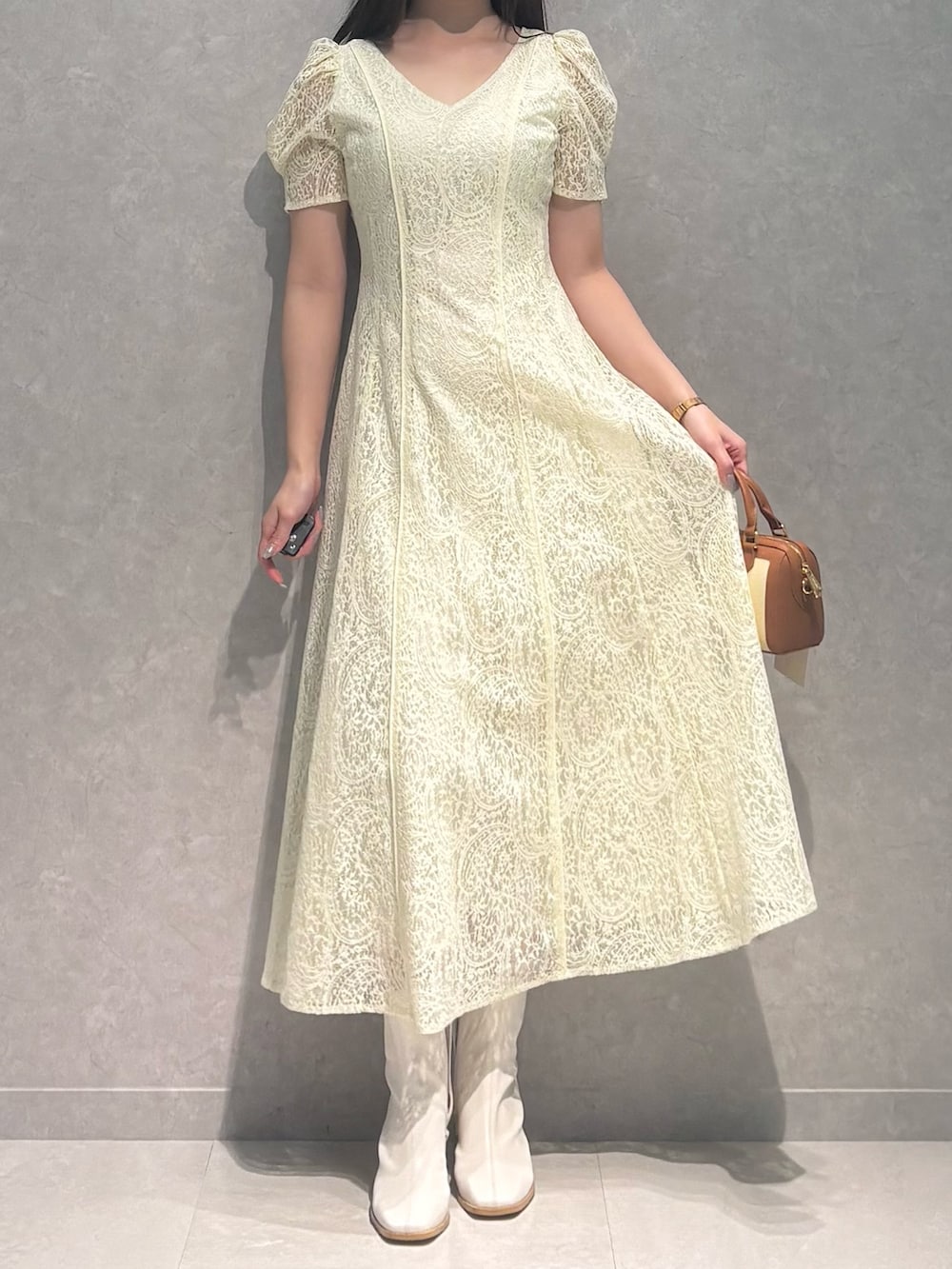 ホワイト系のブーツ、ブラウン系のハンドバッグ、イエロー系のワンピースを着用したレディースの春コーディネートの3枚目の写真