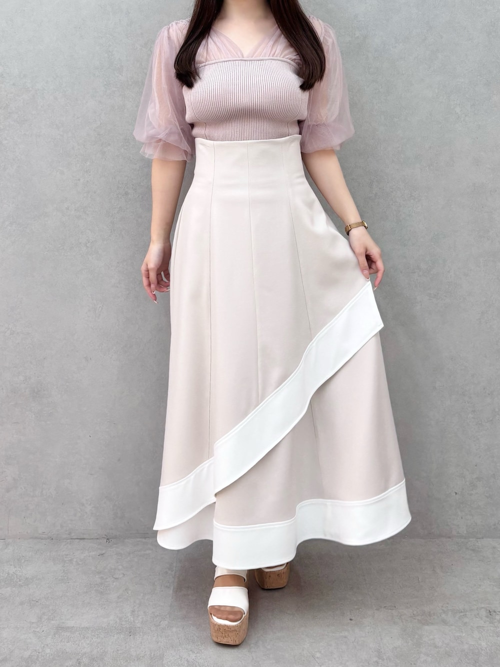 ベージュ系のスカート、ホワイト系のサンダル、ピンク系のニット/セーターを着用したレディースの春コーディネートの2枚目の写真