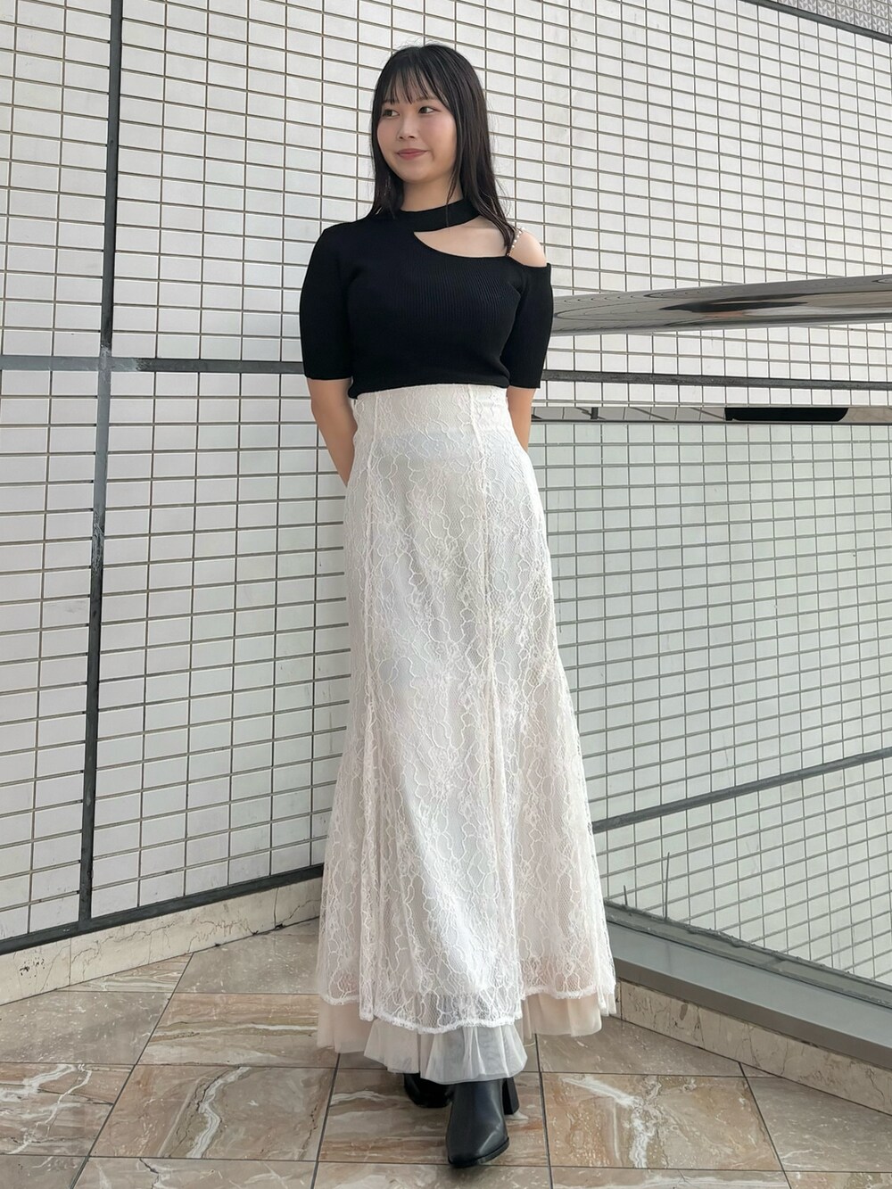 ホワイト系のスカート、ブラック系のブーツ、ブラック系のニット/セーターを着用したレディースの秋コーディネートの2枚目の写真