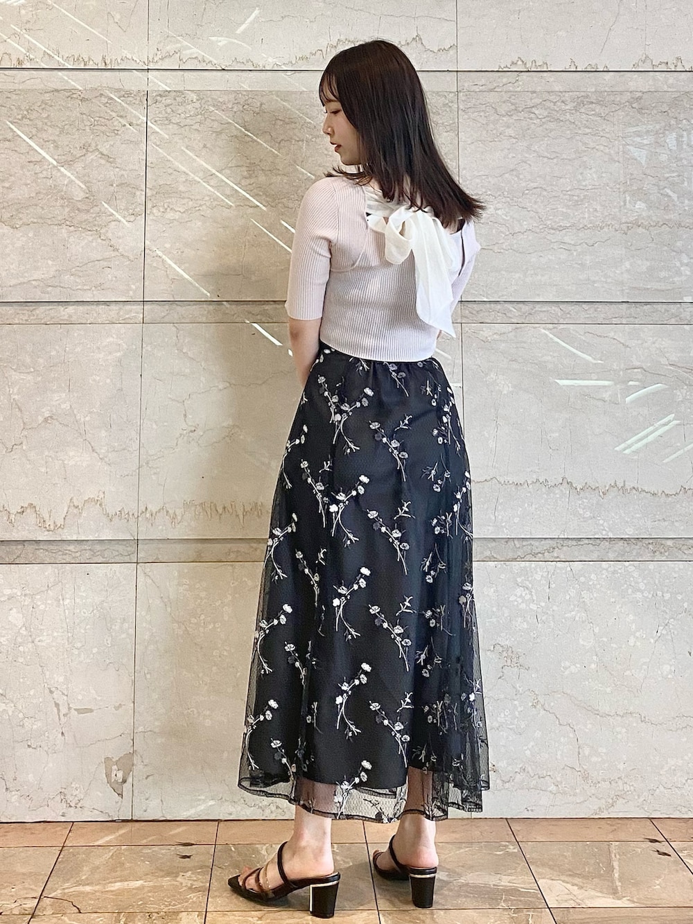 ブラック系のハンドバッグ、グレー系のスカート、ブラック系のサンダルを着用したレディースの春コーディネートの3枚目の写真