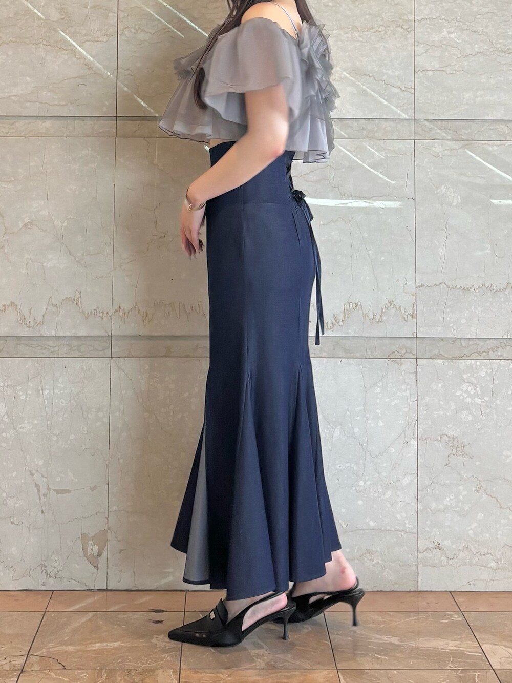 ブルー系のスカート、ブラック系のパンプス、グレー系のシャツ/ブラウスを着用したレディースの夏コーディネートの3枚目の写真