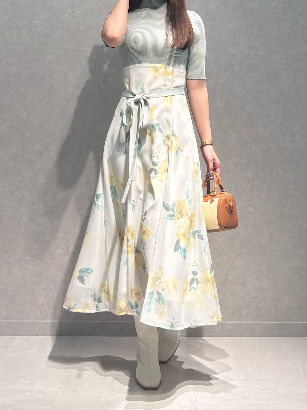 グリーン系のワンピース、ホワイト系のブーツ、ブラウン系のハンドバッグを着用したレディースの春コーディネートの3枚目の写真