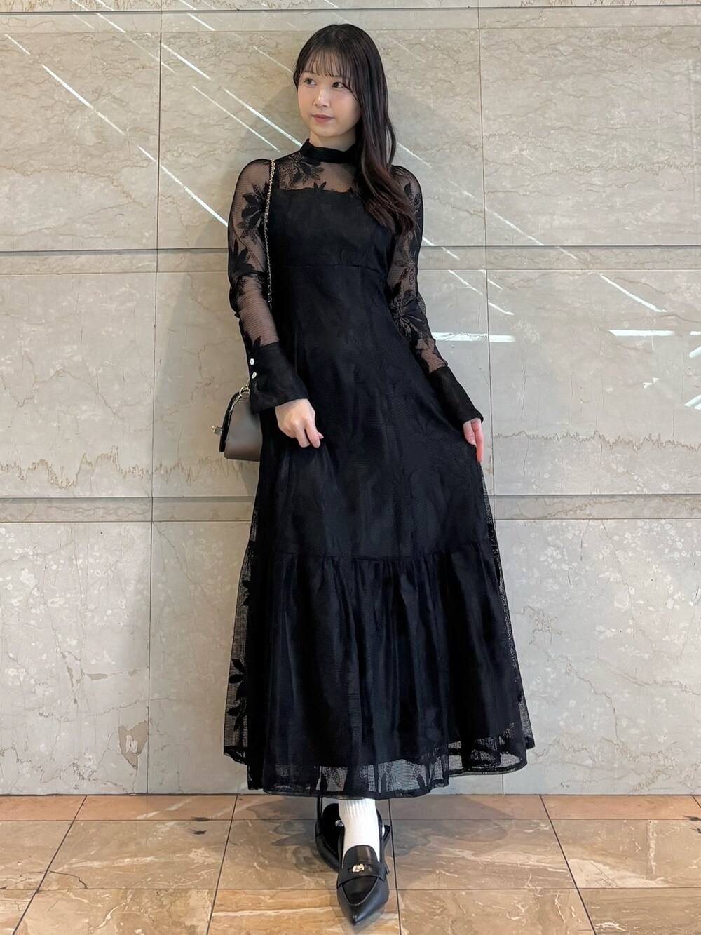 ブラウン系のハンドバッグ、ブラック系のパンプス、ブラック系のワンピースを着用したレディースの冬コーディネートの2枚目の写真