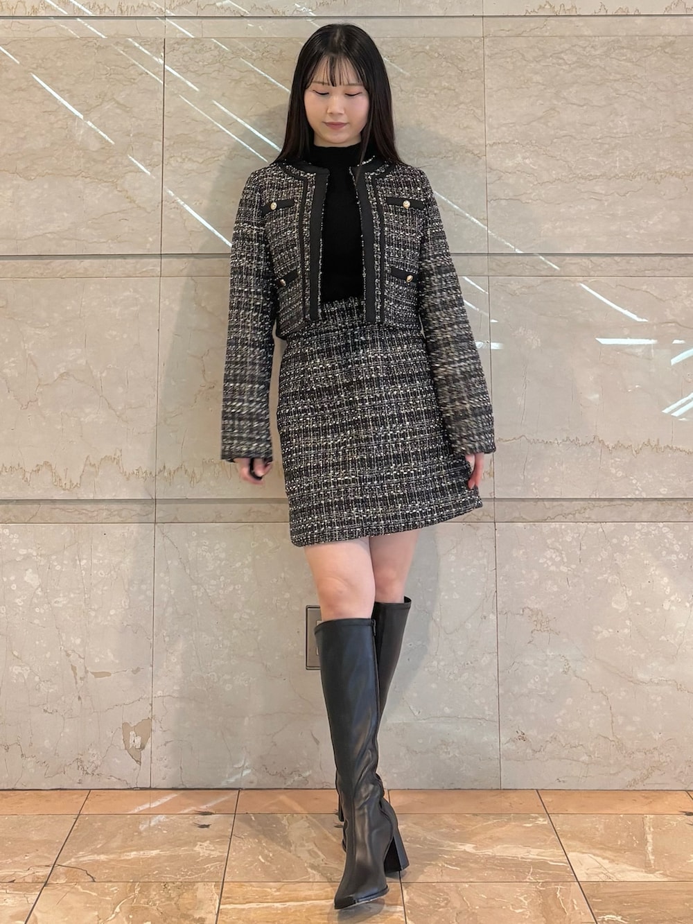 ブラック系のスカート、ブラック系のテーラードジャケット、ブラウン系のブーツを着用したレディースの冬コーディネートの2枚目の写真