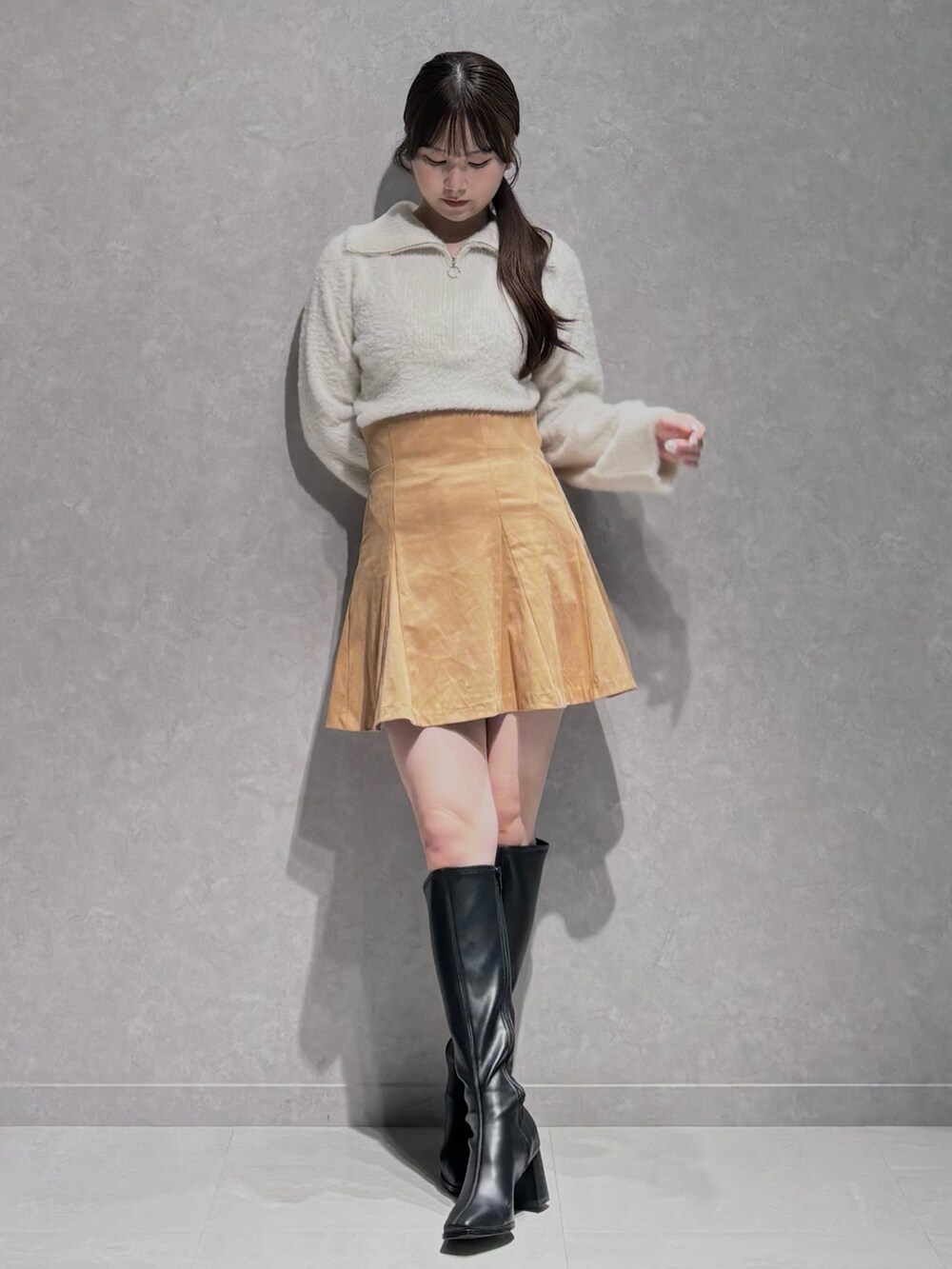 イエロー系のスカート、ホワイト系のニット/セーター、ブラック系のブーツを着用したレディースの秋コーディネートの3枚目の写真