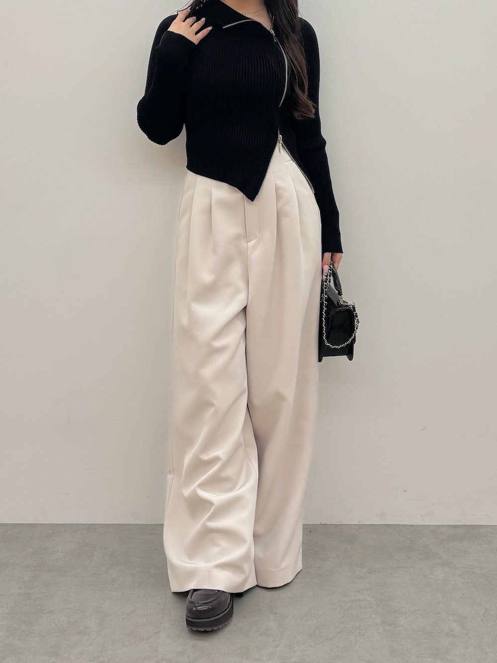 ブラック系のニット/セーター、ブラック系のハンドバッグ、ブラウン系のブーツを着用したレディースの秋コーディネートの2枚目の写真