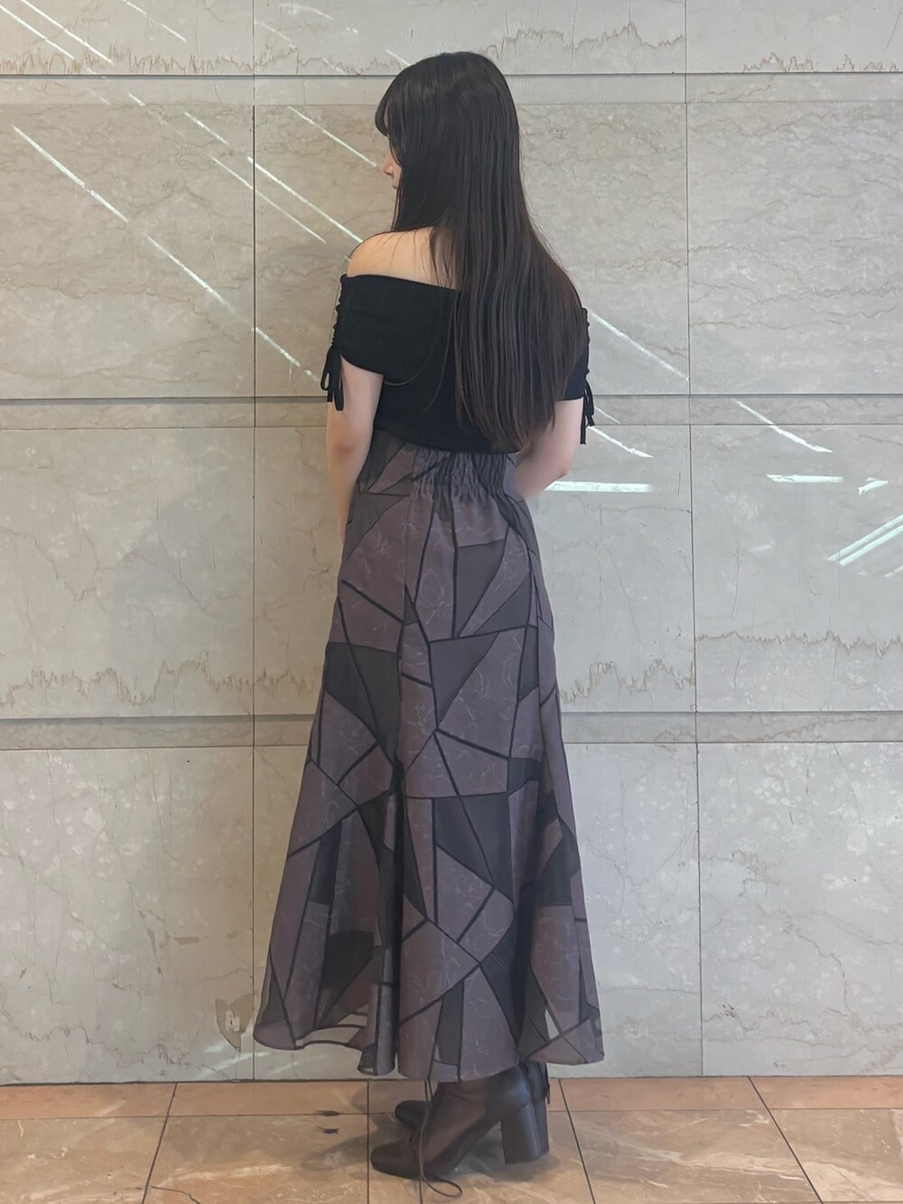 ブラウン系のブーツ、ブラウン系のスカート、ブラック系のニット/セーターを着用したレディースの夏コーディネートの3枚目の写真