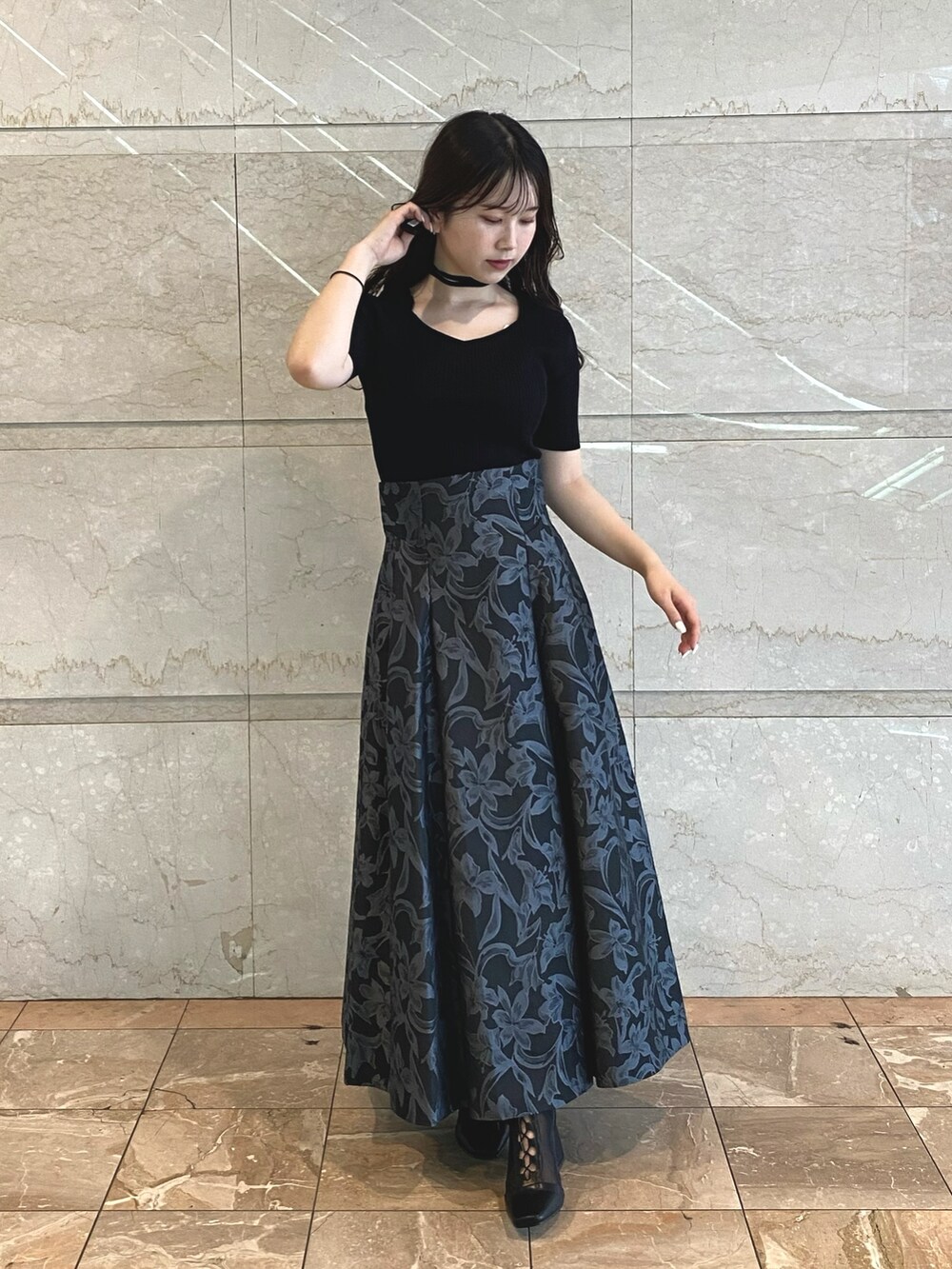 グレー系のスカート、ブラック系のブーツ、ホワイト系のニット/セーターを着用したレディースの秋コーディネートの2枚目の写真