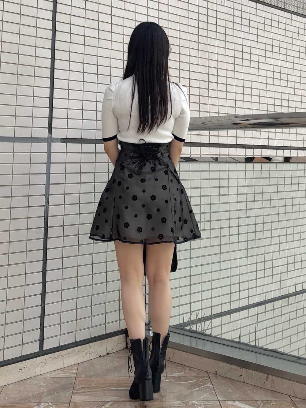 ブラック系のスカート、ブラック系のブーツ、ホワイト系のニット/セーターを着用したレディースの春コーディネートの4枚目の写真