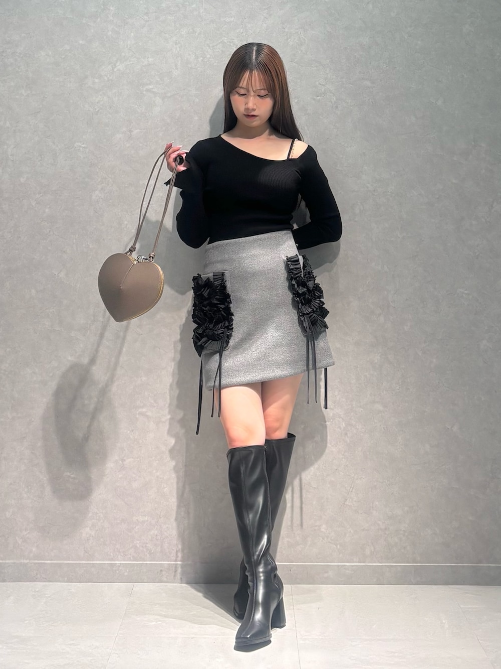 グレー系のスカート、ベージュ系のショルダーバッグ、ブラック系のニット/セーターを着用したレディースの冬コーディネートの2枚目の写真