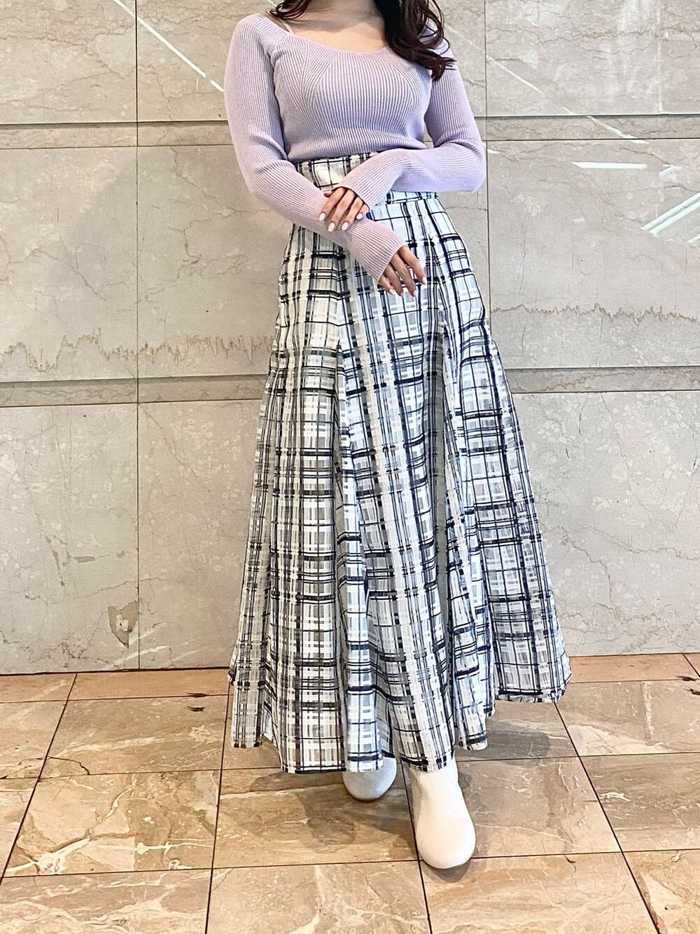 パープル系のニット/セーター、ホワイト系のスカート、ホワイト系のブーツを着用したレディースの冬コーディネートの2枚目の写真