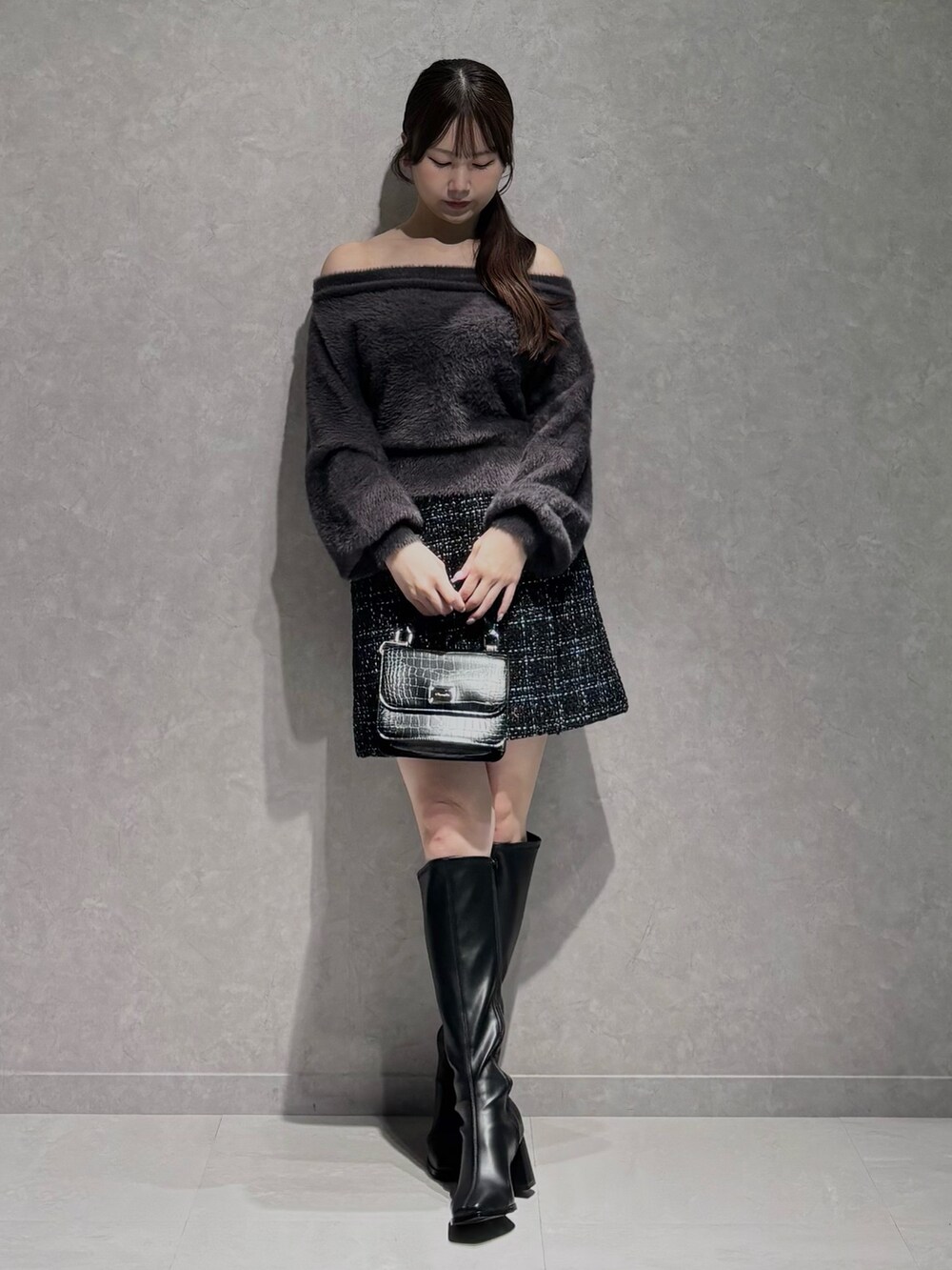 ブラック系のスカート、グレー系のニット/セーター、ブラック系のハンドバッグを着用したレディースの秋コーディネートの3枚目の写真
