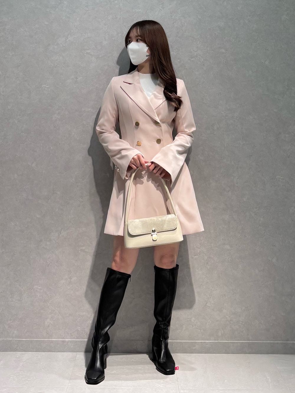 ピンク系のワンピース、ホワイト系のハンドバッグ、ブラック系のブーツを着用したレディースの春コーディネートの3枚目の写真