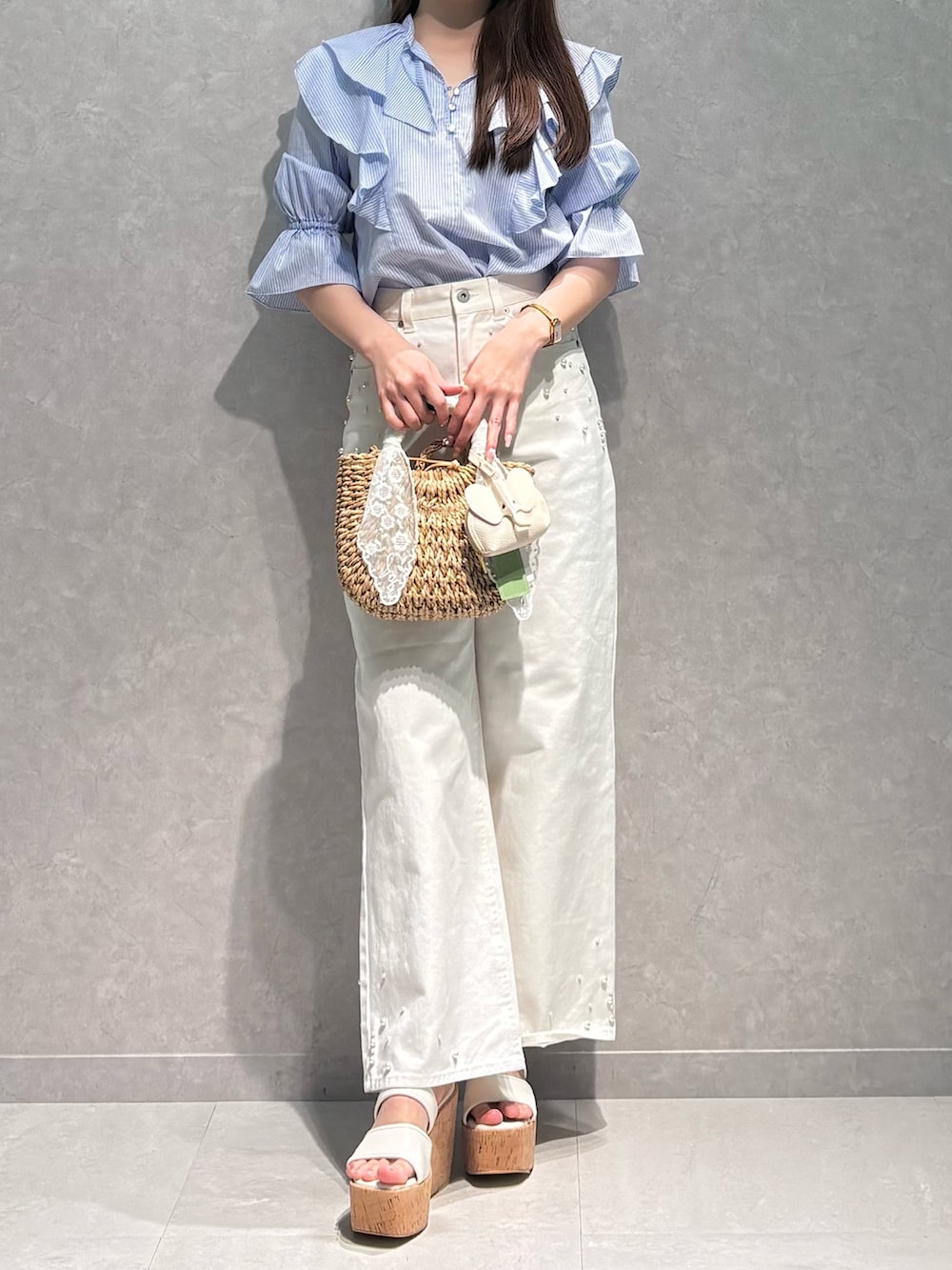 ホワイト系のデニムパンツ、ブルー系のシャツ/ブラウス、ベージュ系のハンドバッグを着用したレディースの春コーディネートの3枚目の写真