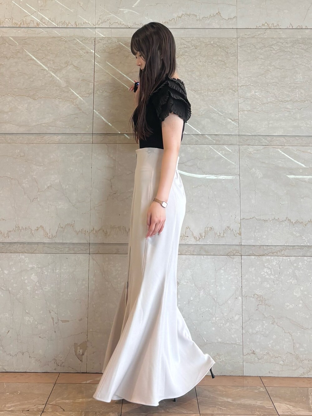 グレー系のスカート、ブラック系のニット/セーター、ブラック系のパンプスを着用したレディースの夏コーディネートの3枚目の写真