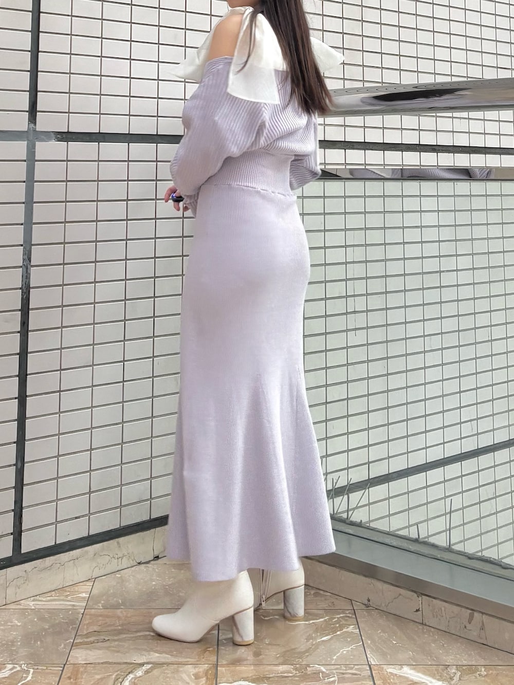 パープル系のワンピース、ホワイト系のブーツを着用したレディースの冬コーディネートの3枚目の写真