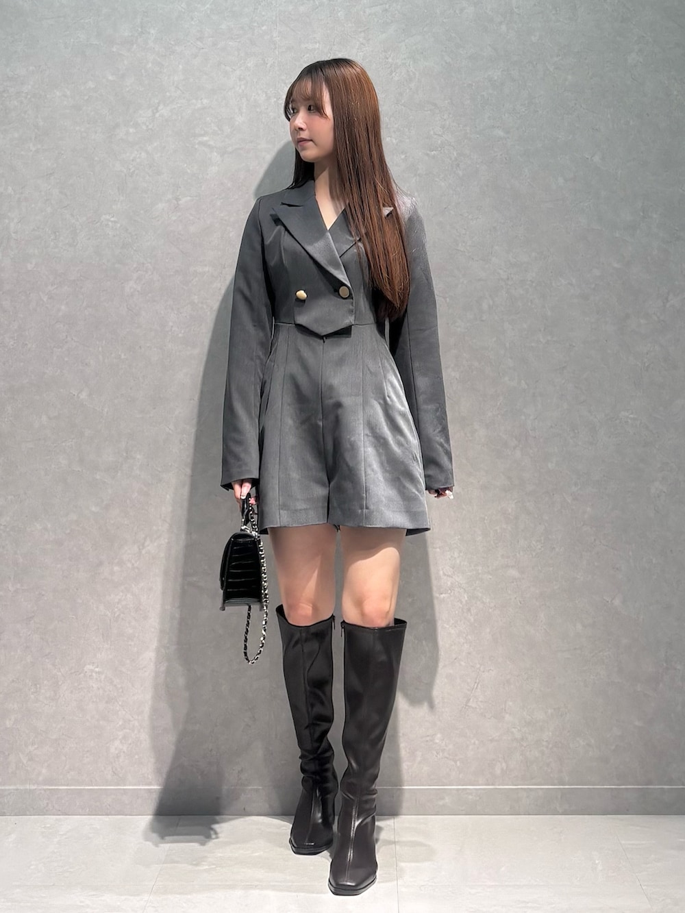 グレー系のつなぎ/オールインワン、ブラウン系のブーツ、ブラック系のハンドバッグを着用したレディースの冬コーディネートの2枚目の写真