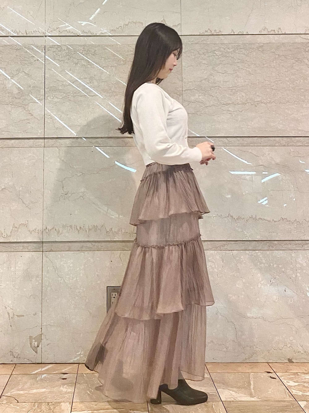 ブラウン系のスカート、ホワイト系のカーディガン/ボレロ、ブラウン系のブーツを着用したレディースの冬コーディネートの3枚目の写真