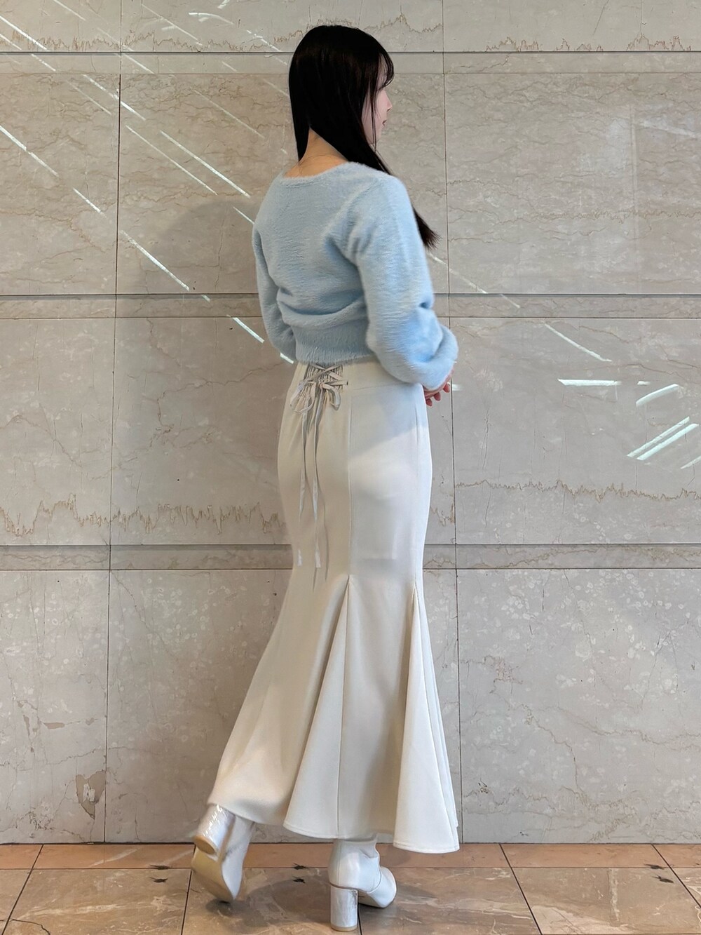 ホワイト系のブーツ、ブルー系のカーディガン/ボレロ、ホワイト系のスカートを着用したレディースの冬コーディネートの4枚目の写真