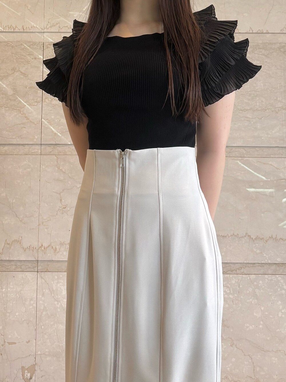 グレー系のスカート、ブラック系のニット/セーター、ブラック系のパンプスを着用したレディースの夏コーディネートの4枚目の写真