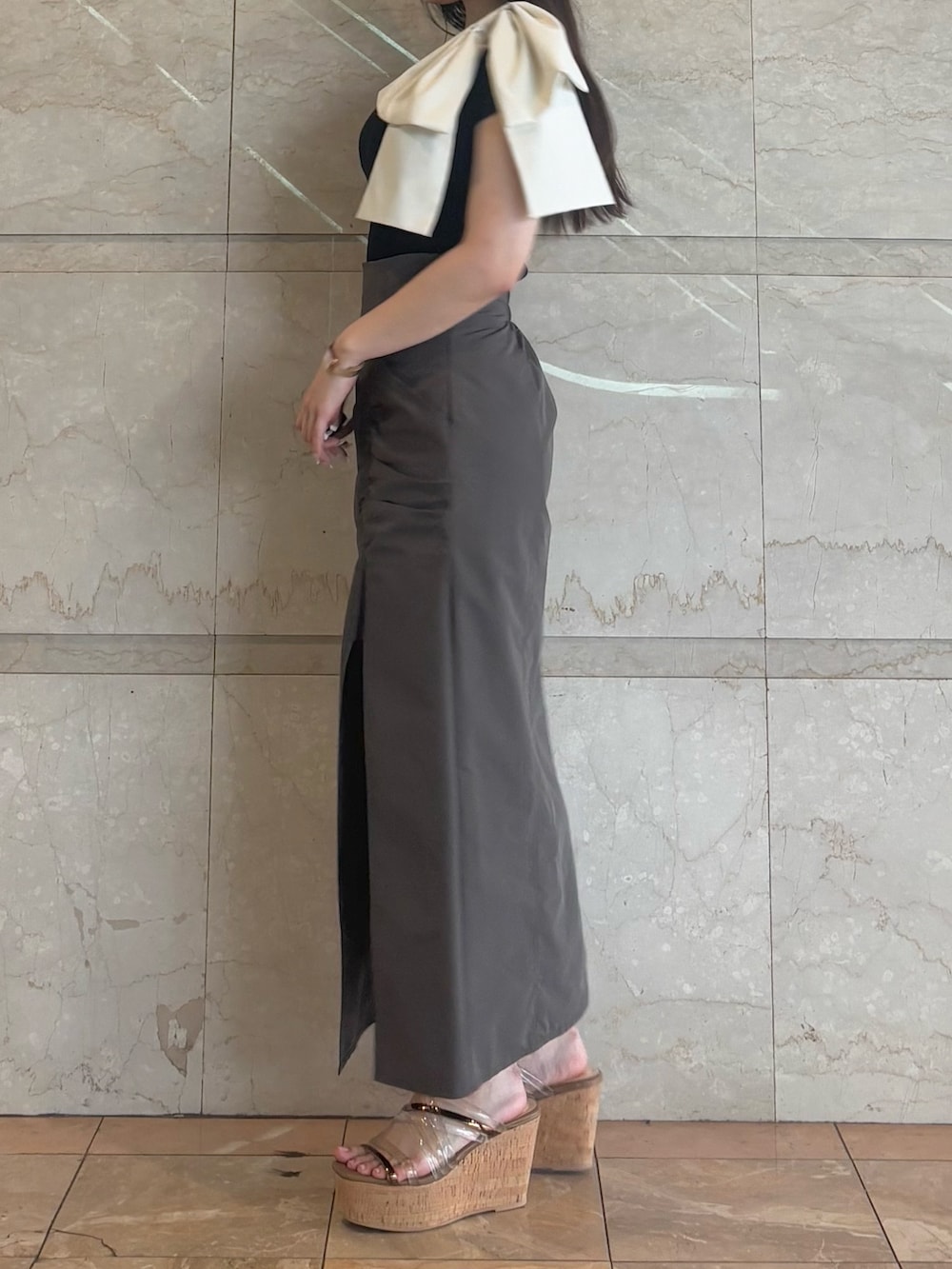 ブラウン系のスカート、ブラウン系のサンダル、ブラック系のニット/セーターを着用したレディースの夏コーディネートの3枚目の写真