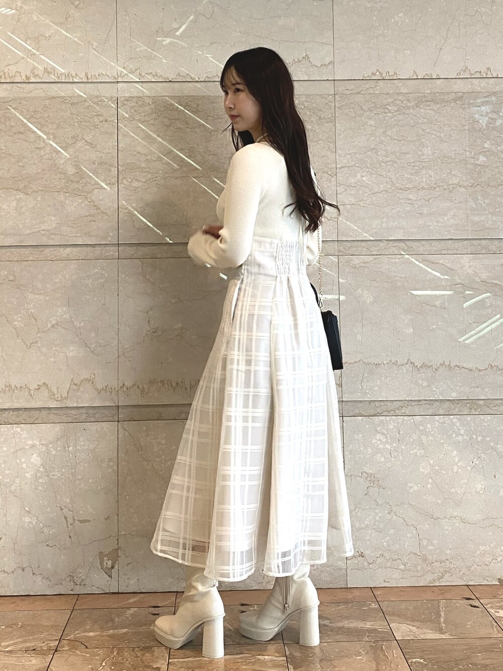 ホワイト系のワンピース、ホワイト系のブーツ、ブラック系のショルダーバッグを着用したレディースの秋コーディネートの8枚目の写真