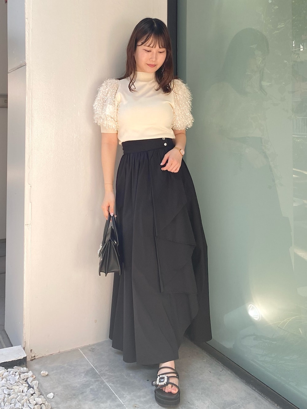 ブラック系のショルダーバッグ、ブラック系のサンダル、ブラック系のスカートを着用したレディースの夏コーディネートの2枚目の写真