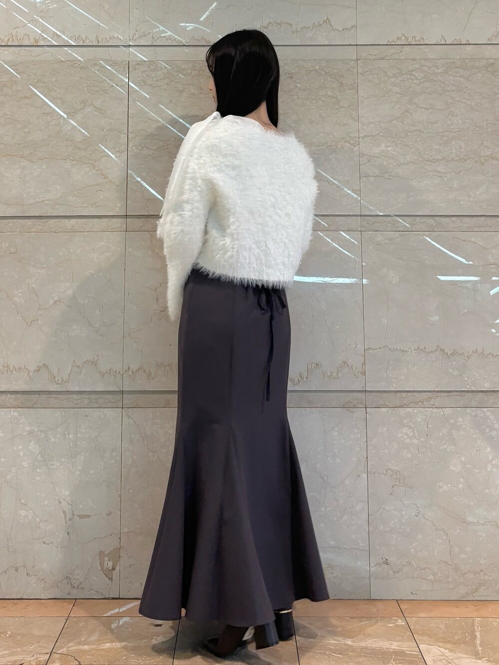 グレー系のスカート、ブラウン系のブーツ、ホワイト系のニット/セーターを着用したレディースの冬コーディネートの4枚目の写真