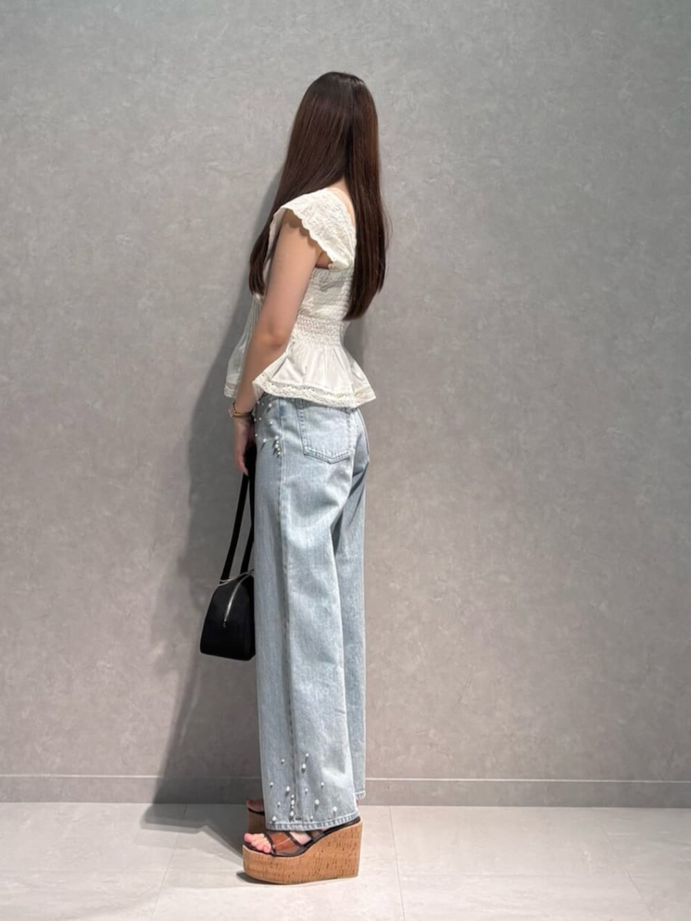 ブルー系のデニムパンツ、ブラウン系のサンダル、ホワイト系のシャツ/ブラウスを着用したレディースの夏コーディネートの4枚目の写真