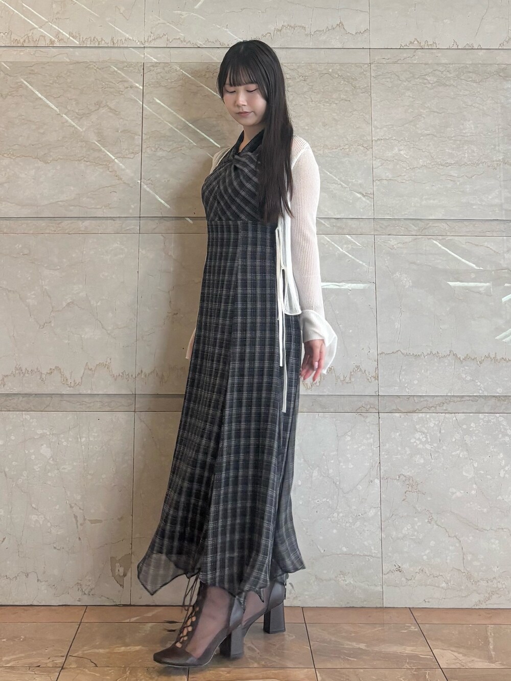 ブラック系のワンピース、ホワイト系のカーディガン/ボレロ、ブラウン系のブーツを着用したレディースの夏コーディネートの2枚目の写真