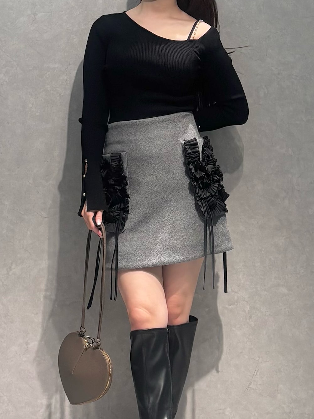 グレー系のスカート、ベージュ系のショルダーバッグ、ブラック系のニット/セーターを着用したレディースの冬コーディネートの6枚目の写真