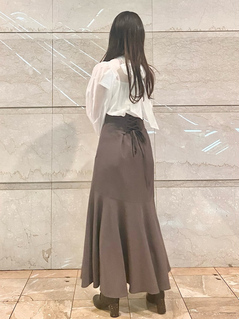 ブラウン系のスカート、ホワイト系のシャツ/ブラウス、ブラウン系のブーツを着用したレディースの冬コーディネートの3枚目の写真