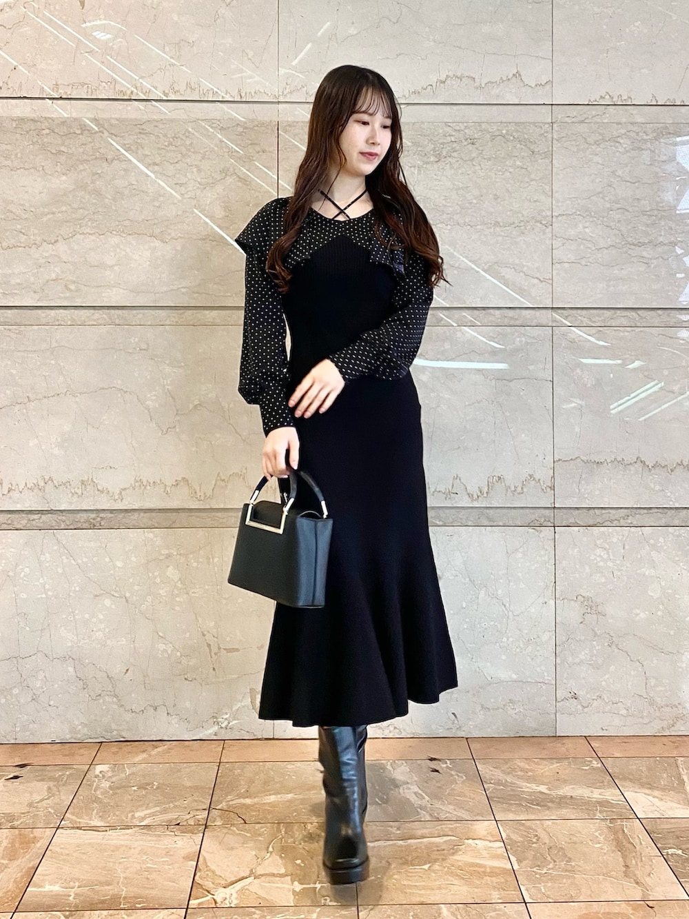 ブラック系のワンピース、ブラック系のブーツ、ブラック系のハンドバッグを着用したレディースの秋コーディネートの4枚目の写真