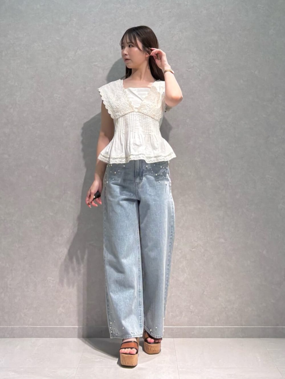ブルー系のデニムパンツ、ブラウン系のサンダル、ホワイト系のシャツ/ブラウスを着用したレディースの夏コーディネートの2枚目の写真